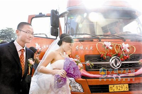 新郎新娘在东风天龙的婚车前合影